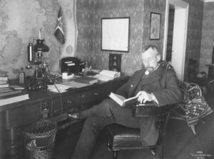 Roald Amundsen in his office, reading a book.