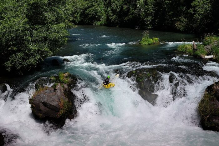 A packrafter is pictured descending a small waterfall