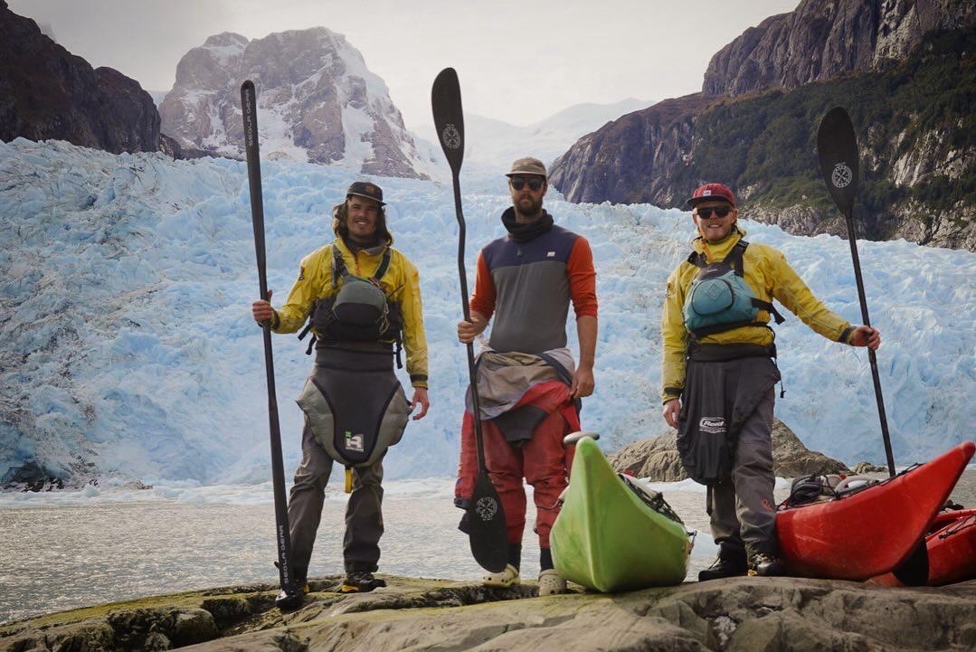 three kayakers stand by Patagonian fiord