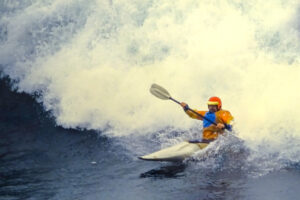 paddler as a huge wave breaks behind him