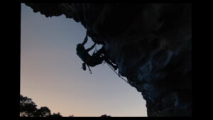 A climber outlined against a purple sky