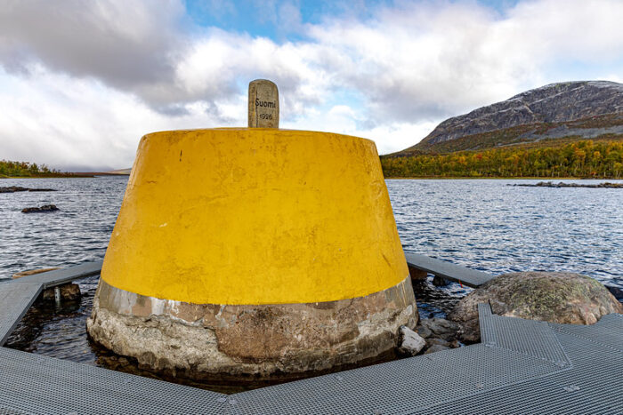 yellow cone-shaped concrete structure at a mountain lake.