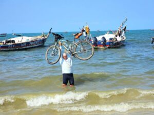 guy standing in ocean holding bike