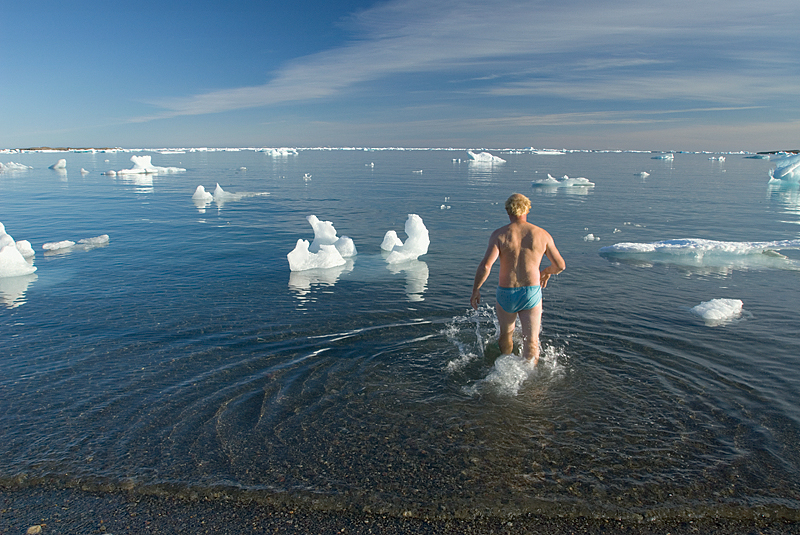 man stepping into ice water in Arctic