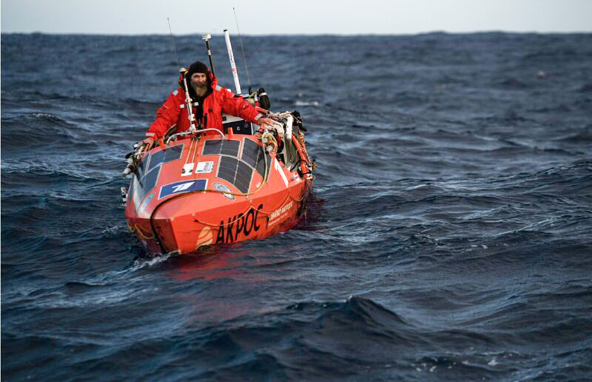 ocean rower poses in his orange boat