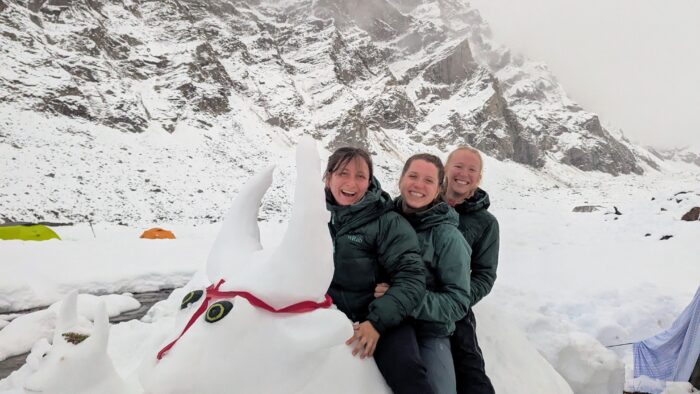 Three girls on a snow yak in a snowy base camp.