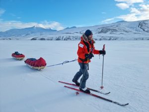 A man on skis drags two sleds behind him over the snow.