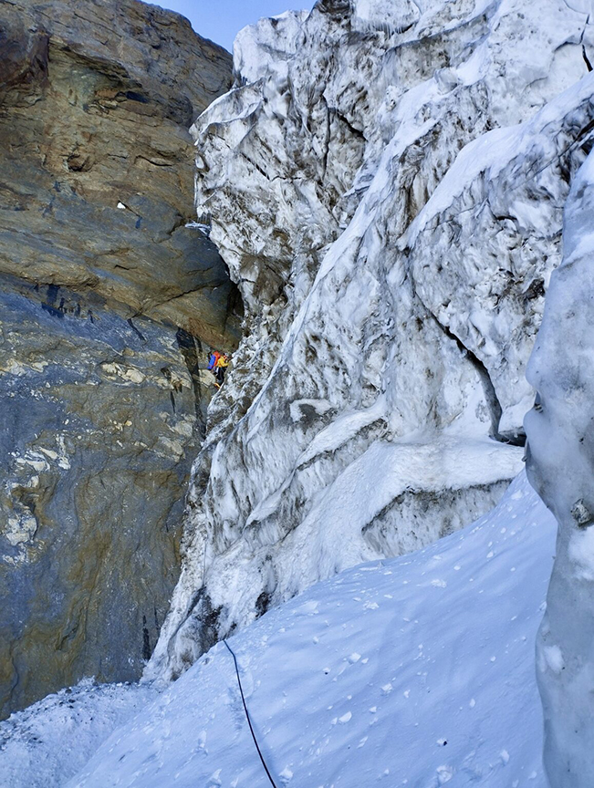 A climber on a difficult mixed section of a big face.
