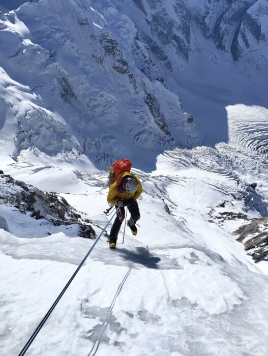 A climber rappelling down a steep ice ramp.