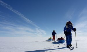 two skiers, moving toward the camera, on the Antarctic plateau