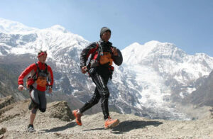 Two runners on a trail with huge mountains in background.