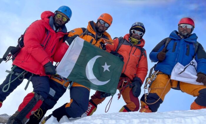 Climbers on a snowy place, apparently a summit, with the sky above them.