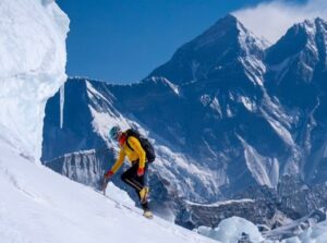 a clibmer goin up a snow ramp with Everest in background.
