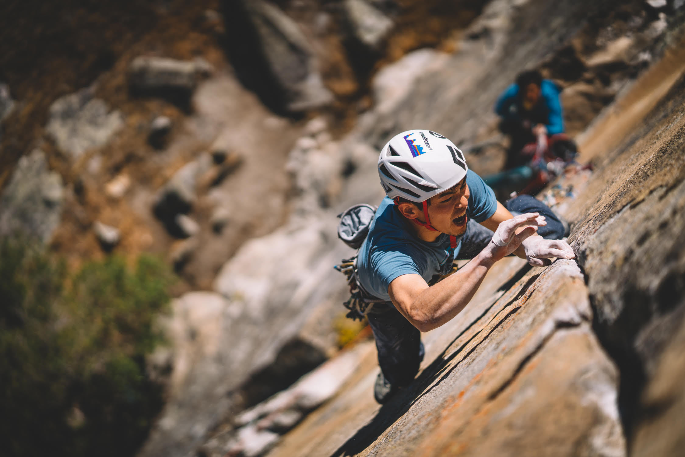 The climber on a granite slab, his face showing the effort