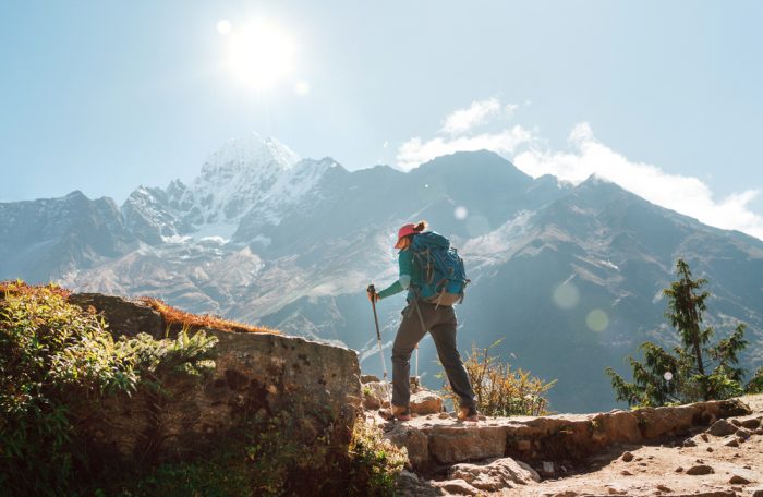 A trekker on a stone trial with a high mountain range in background. 