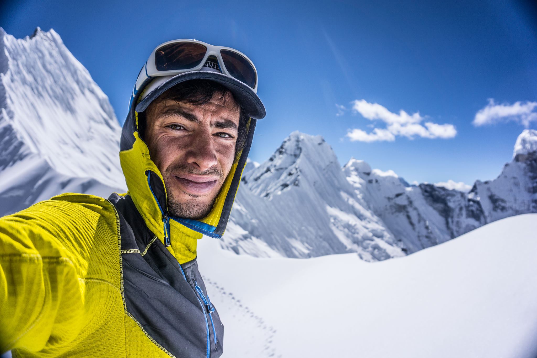 Selfie with anowy mountains in background on a sunny day. Jornet in light mountain clothes.