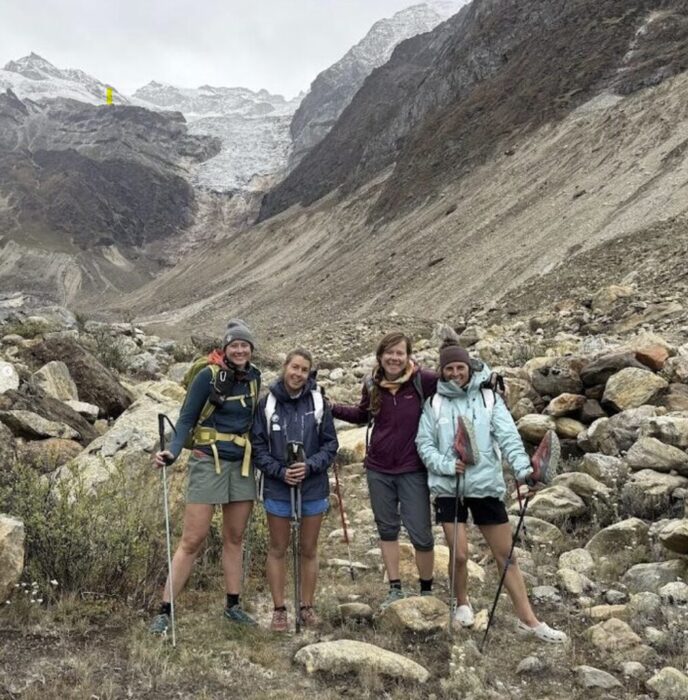 Four female climbers in shorts and jckets at a rocky landscape in India's Himalaya. 