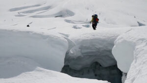 A crevasse and several men hiking past