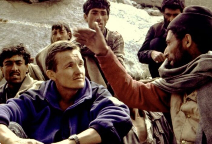 Alexander odintsov, sitting down, listen to a Balti porter speaking withle other locals, sitting around them, listen too.