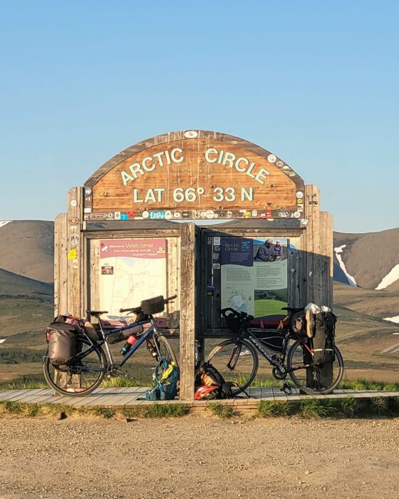 Two bikes by the sign for the Arctic Circle.