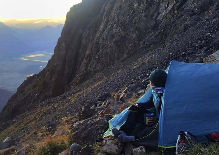person looking out of tent across valley