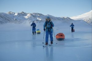 3 skiers sking over bare ice