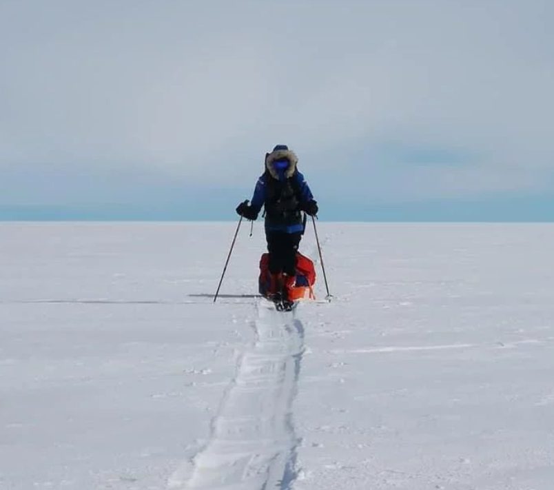A woman skis towards the camera through the snow in Antarctica.