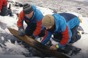 Espen Finstad (Secrets of the Ice) and Julian Post-Melbye (Museum of Cultural History) free an ancient ski from the Digervarden ice patch on Sept. 26, 2021. Image: Glacier Archaeology Program / Secrets of the Ice