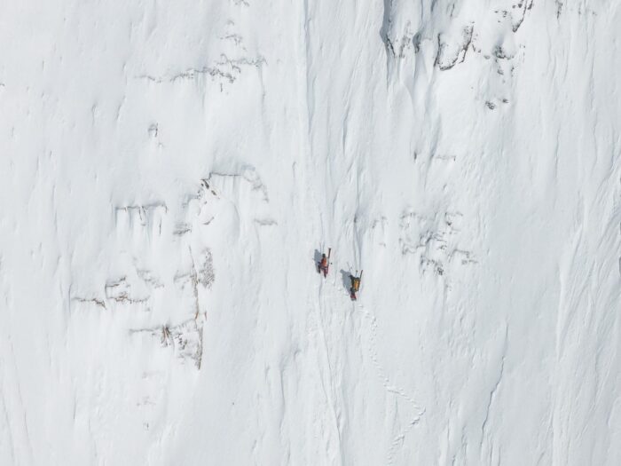 Two climbers on a vertical snow wall. 