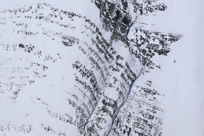 Two skiers on a huge mountain face. 