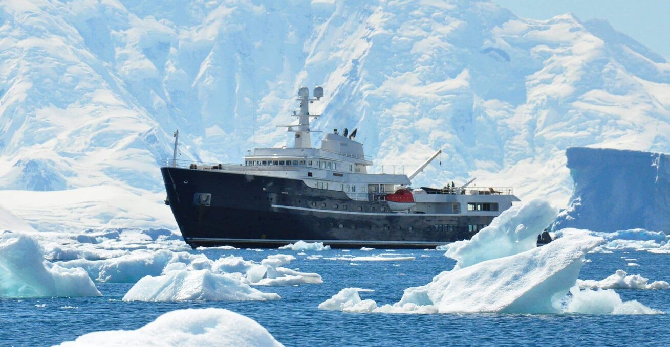 A yacht sitting in a bay surrounded by ice floes.