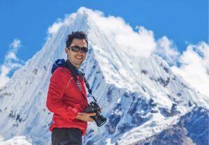 man in red jacket against mountain with camera