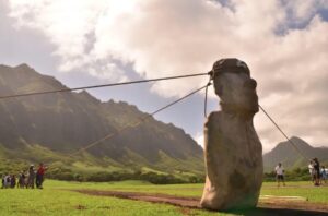 A group of 18 people use ropes to rock the moai statue from side to side.