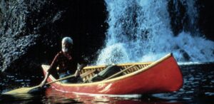 man canoeing by waterfall
