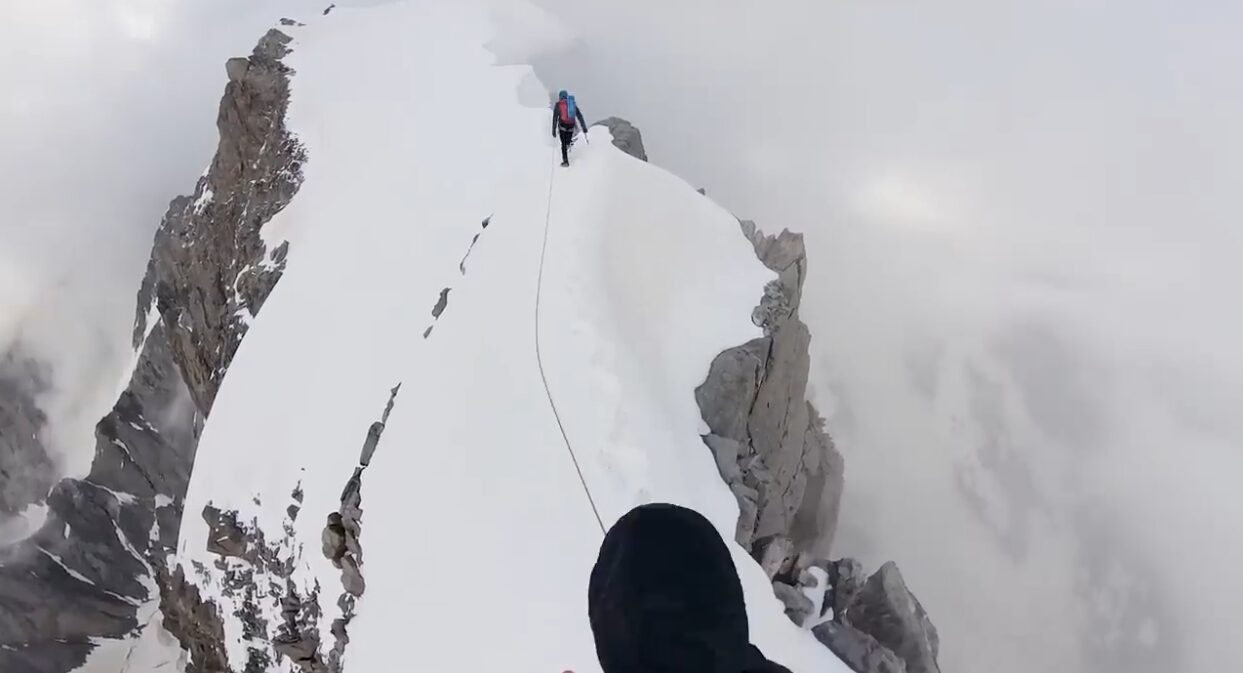 A pair of climbers tethered together on a mountain ridge