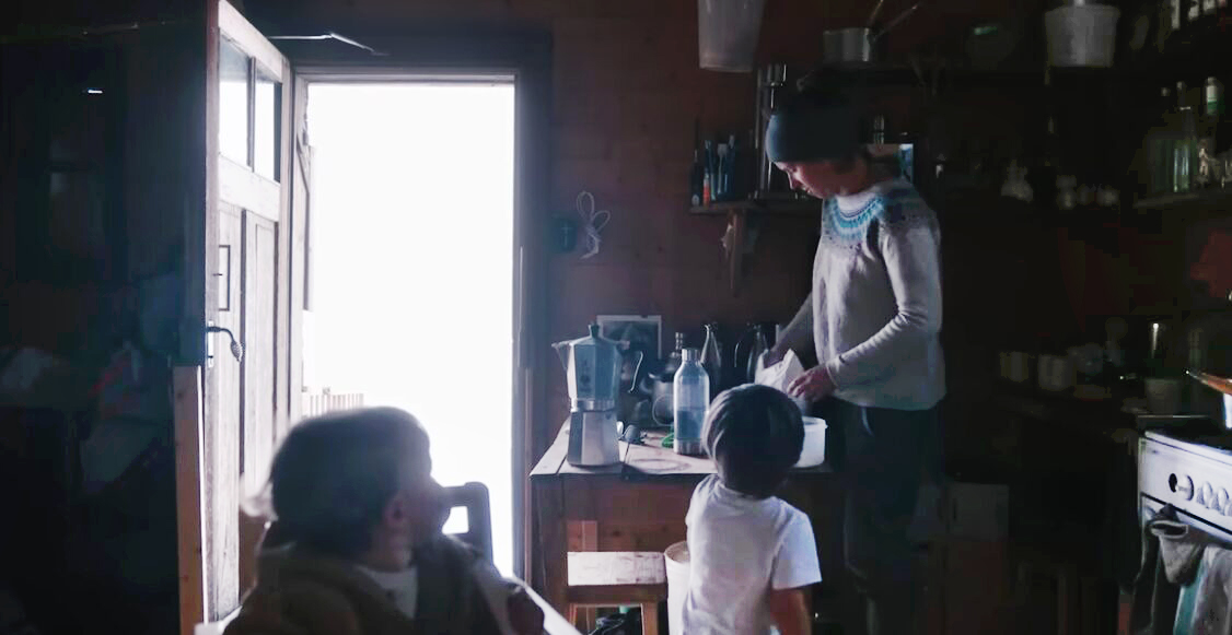 woman and two kids inside dark mountain hut
