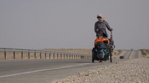 walker pushing cart along barren road