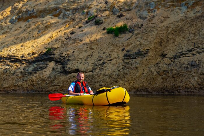 A solo packrafter is pictured wearing a life vest