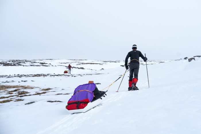 two men pulling sleds