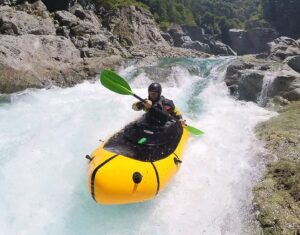 A climber paddling white waters in a packraft.