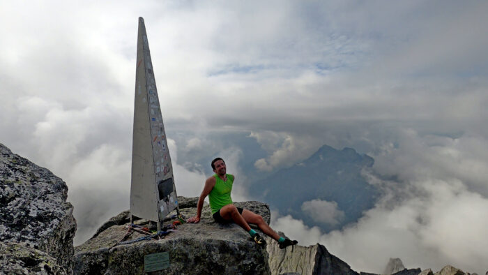 climber on top of peak beside obelisk