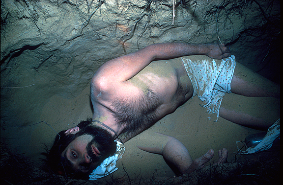 man lying in sandy pit