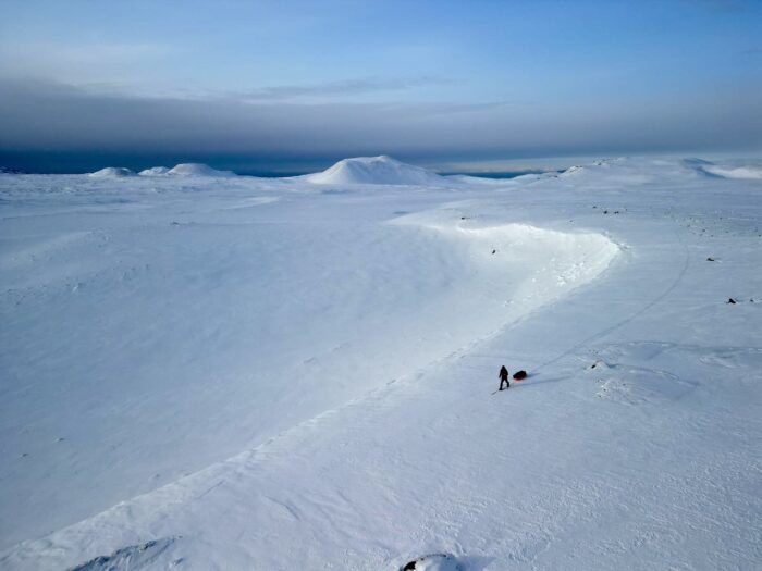 a skier with a sled on a snowy cornice line