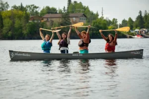 four female canoeists raise their paddles in the air