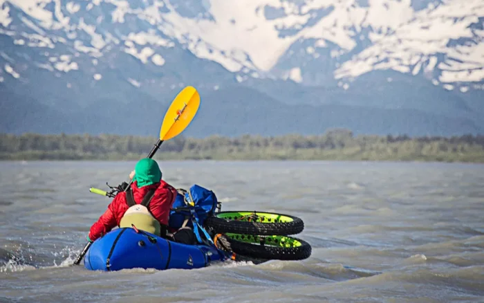 A man paddles a laden packraft on the Dangerous River, Alaska