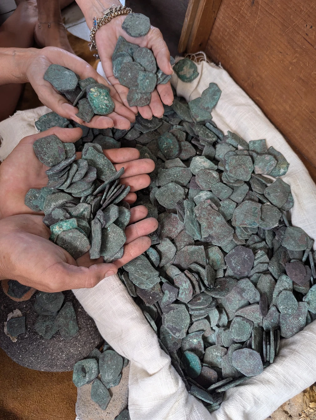 Two people holding handfuls of antique silver coins.